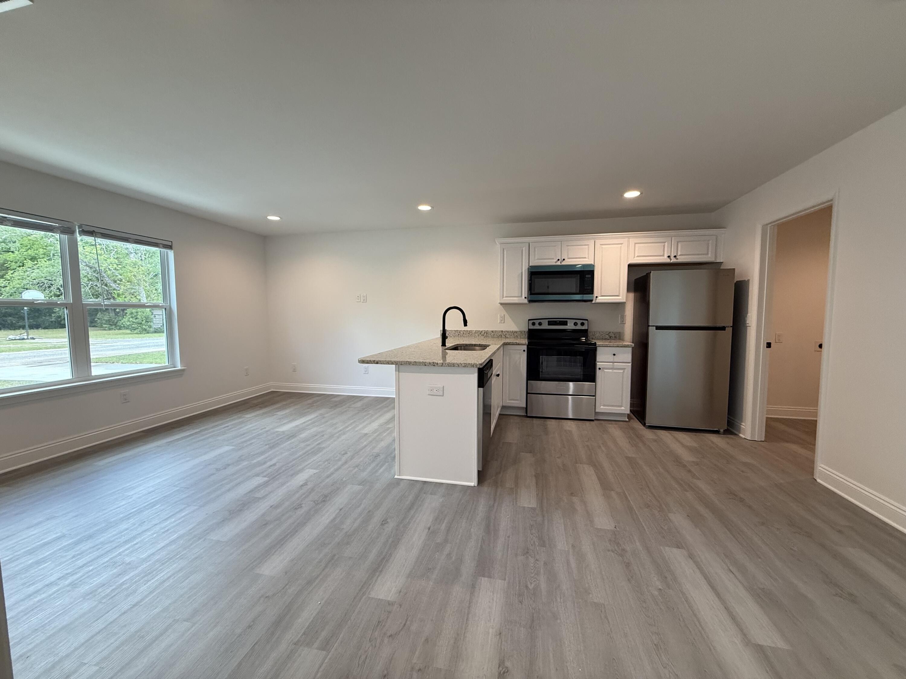32 Constitution Avenue, Unit AB DeFuniak Springs, FL 32433 - Photo 7 of 22 a kitchen with stainless steel appliances a refrigerator and a wooden floor