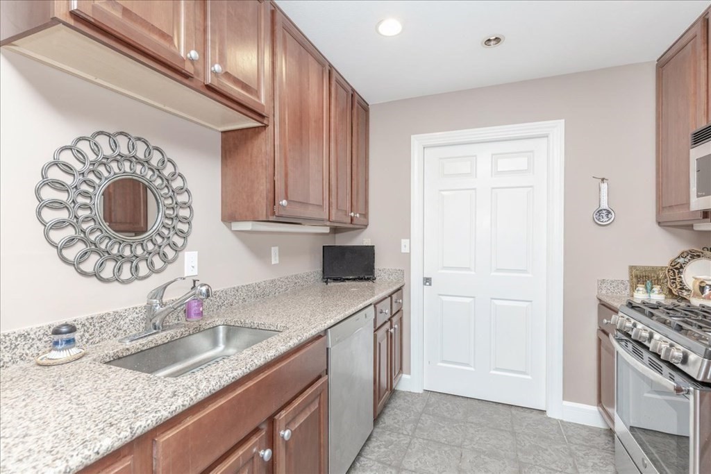 36 Village Road, Unit 706 Middleton, MA 01949 - Photo 9 of 42 a kitchen with granite countertop a sink a stove and cabinets