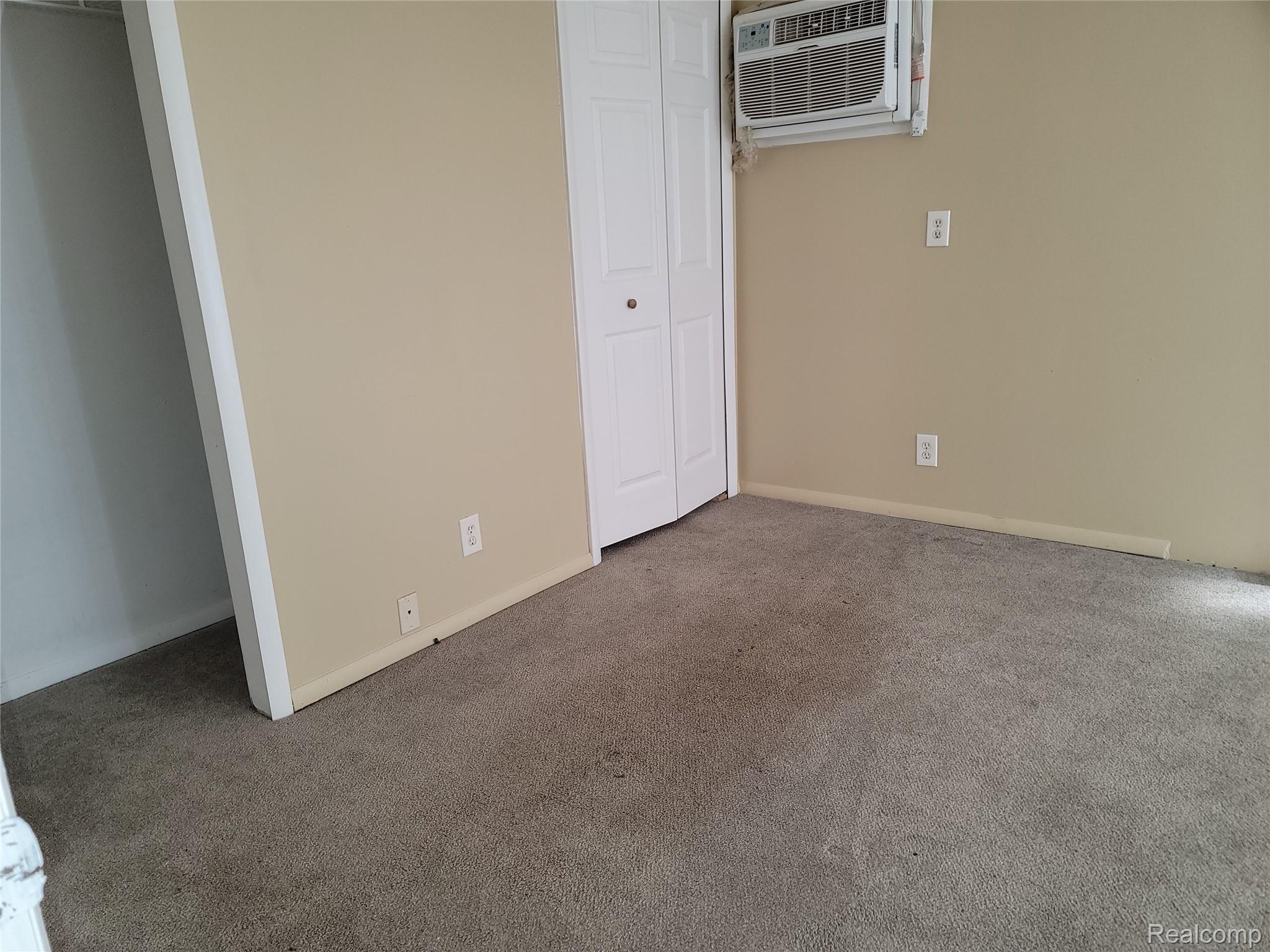 16470 East 9 Mile Road, Unit 104 Eastpointe, MI 48021 - Photo 8 of 14 Unfurnished bedroom with carpet flooring, a closet, and an AC wall unit