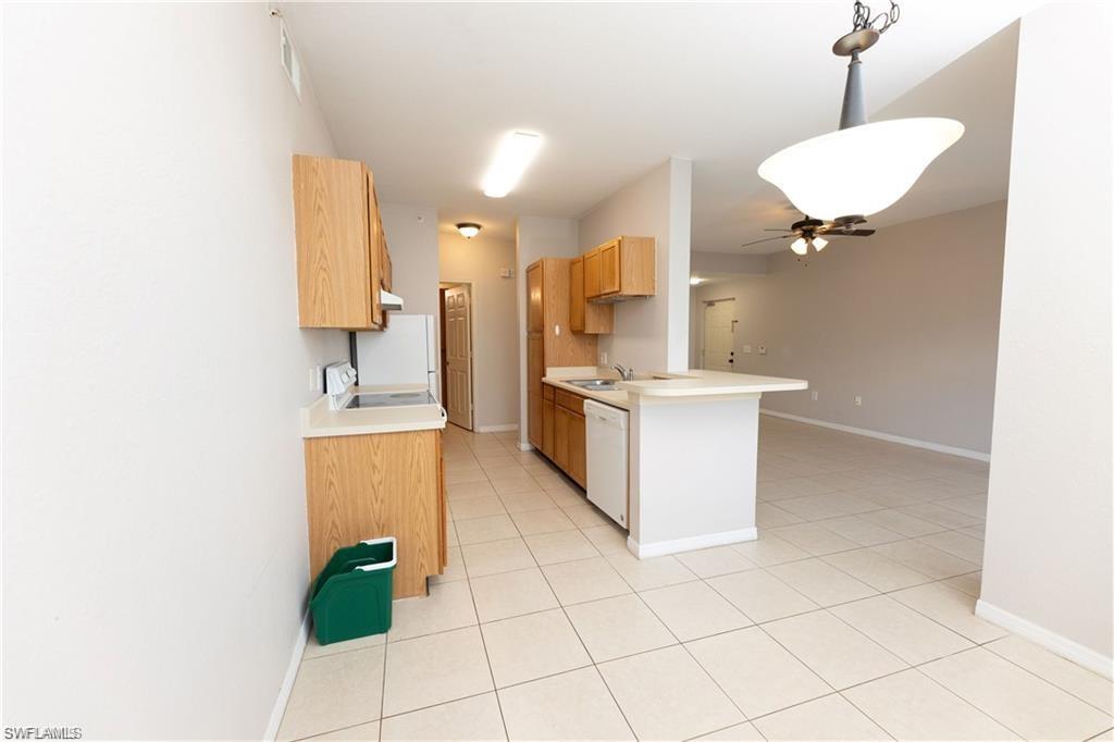 7975 Preserve Circle, Unit 1013 Naples, FL 34119 - Photo 8 of 16 a kitchen with stainless steel appliances kitchen island granite countertop a sink a stove a chimney a microwave and a refrigerator