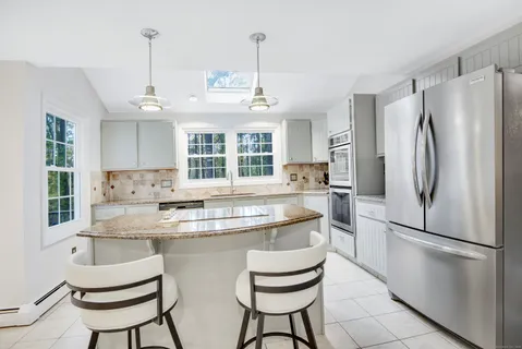 a kitchen with stainless steel appliances granite countertop a sink a stove a refrigerator and island with wooden floor