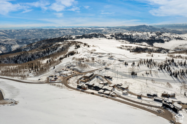 8456 Copper Crest Road, Unit 148 Eden, UT 84310 - Photo 9 of 34 Expansive snow-covered landscape with distant mountain ranges, featuring a cluster of residential structures, a winding paved road, and scattered evergreen trees