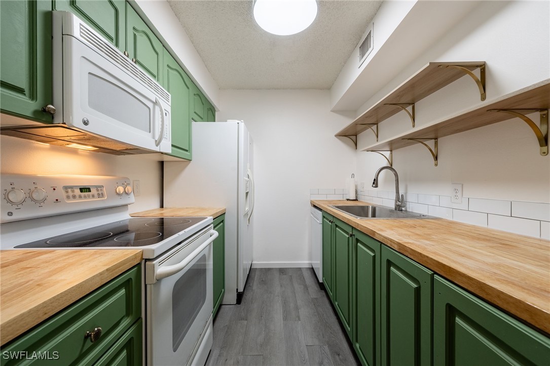 5315 Summerlin Road, Unit 1514 Fort Myers, FL 33919 - Photo 4 of 17 a kitchen with stainless steel appliances granite countertop a sink and dishwasher a stove top oven with wooden floor