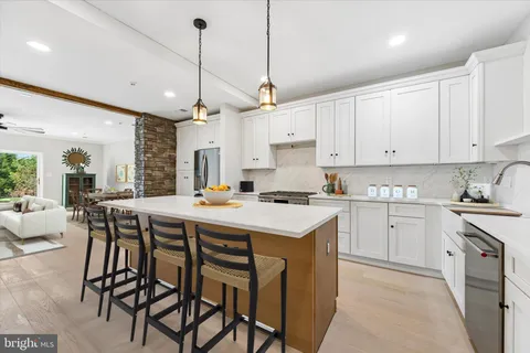 a kitchen with stainless steel appliances granite countertop a sink a stove a refrigerator and island with wooden floor
