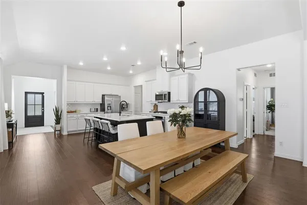 a dining room with wooden floor a chandelier a wooden table and chairs