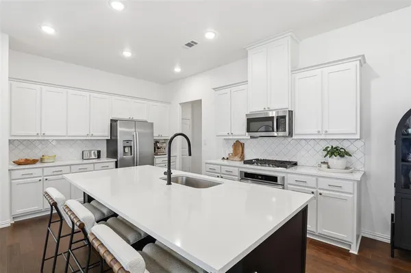 a kitchen with stainless steel appliances a sink a stove a refrigerator cabinets and a dining table