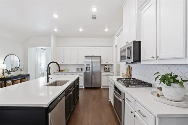 a kitchen with stainless steel appliances granite countertop a sink a stove and refrigerator