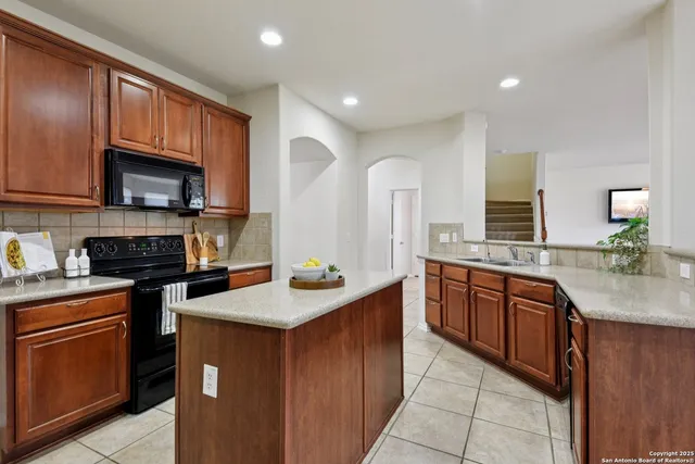 a kitchen with stainless steel appliances granite countertop a refrigerator a stove a sink and a microwave