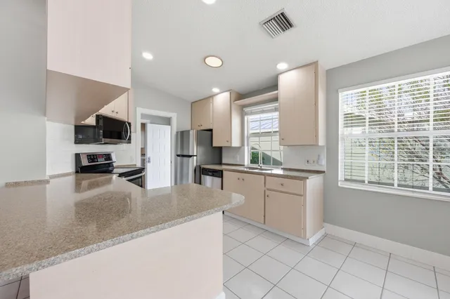a kitchen with granite countertop white cabinets and stainless steel appliances