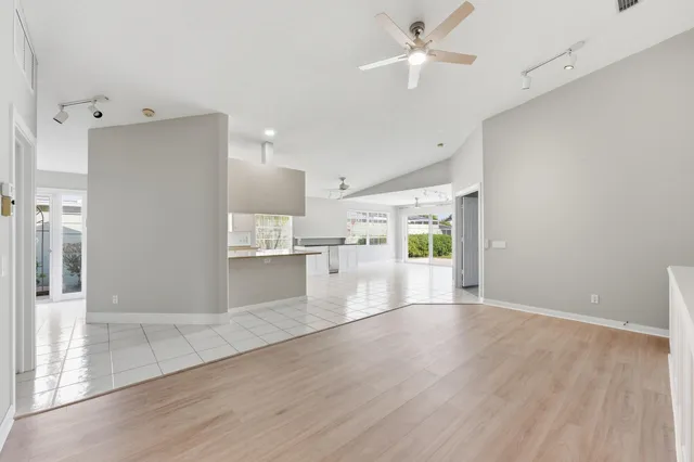 a view of an empty room with kitchen and a window
