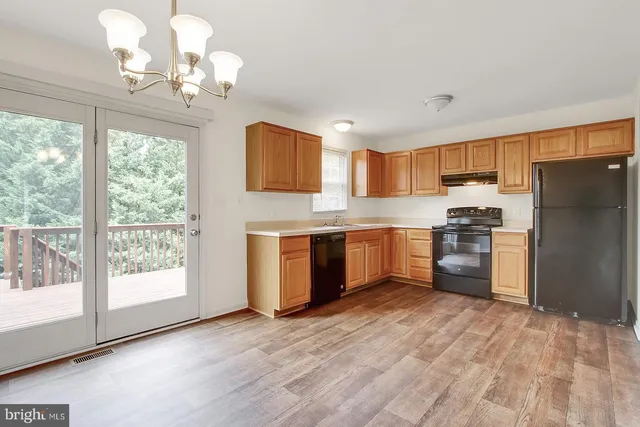 a kitchen with stainless steel appliances granite countertop a refrigerator a sink dishwasher a stove with wooden cabinets and floor