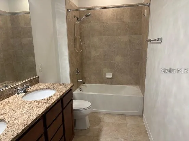 a bathroom with a granite countertop bathtub shower sink vanity and toilet