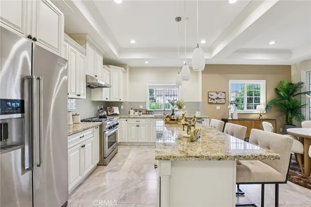 a kitchen with stainless steel appliances granite countertop a kitchen island a stove a table and chairs