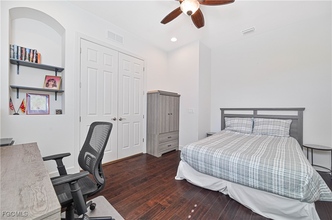 10251 Glastonbury Circle, Unit 201 Fort Myers, FL 33913 - Photo 17 of 45 a bedroom with a bed and a chair with the bookshelf