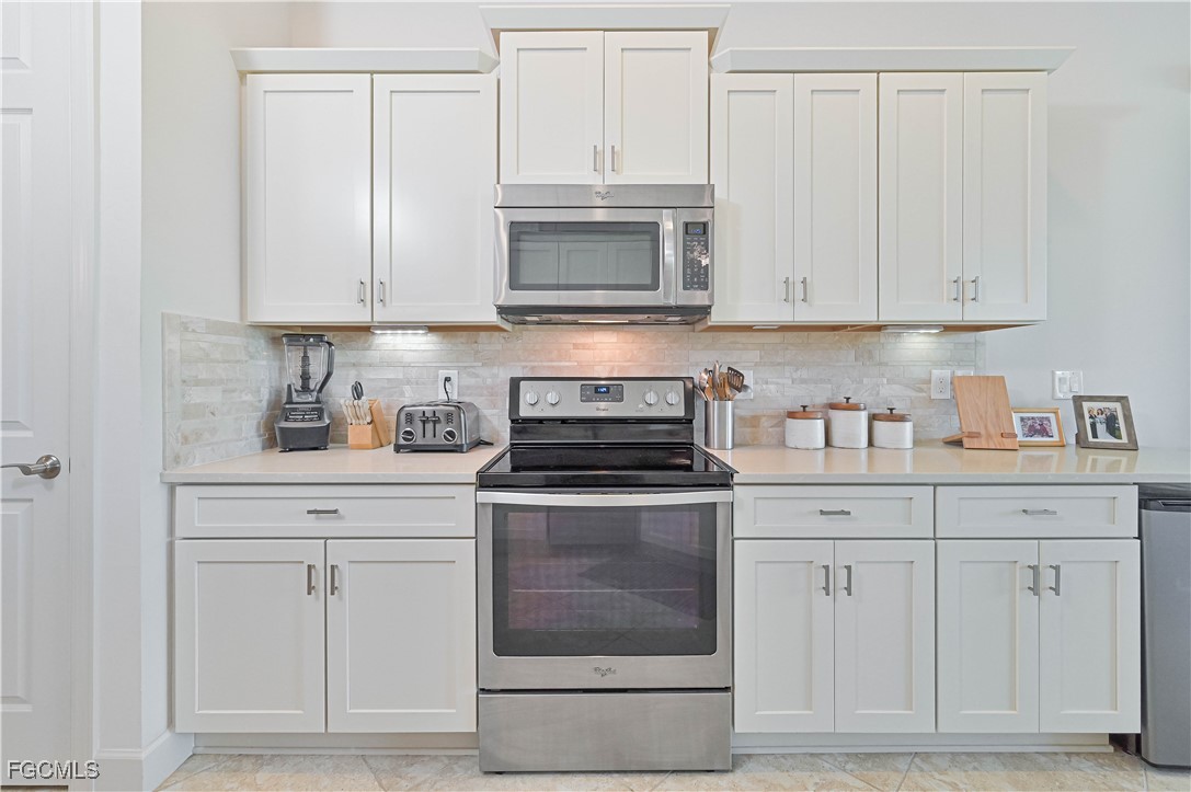 10251 Glastonbury Circle, Unit 201 Fort Myers, FL 33913 - Photo 10 of 45 a kitchen with white cabinets and stainless steel appliances
