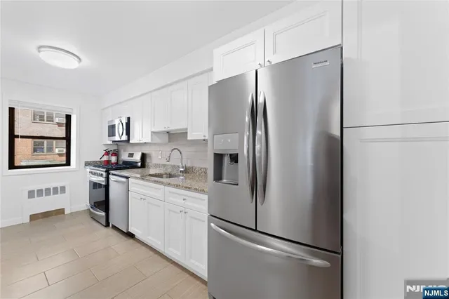 a kitchen with stainless steel appliances a refrigerator sink and white cabinets