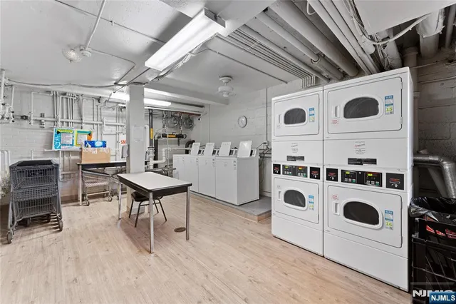 a utility room with stainless steel appliances wooden floor and white cabinets