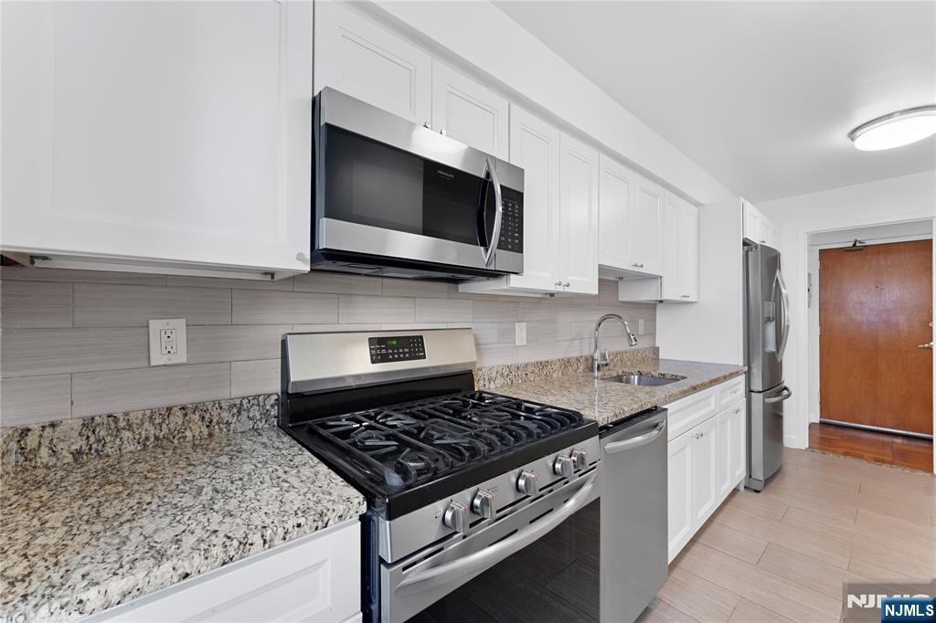 208 Anderson Street, Unit S2A Hackensack, NJ 07601 - Photo 5 of 23 a kitchen with stainless steel appliances kitchen island granite countertop a sink stove and microwave