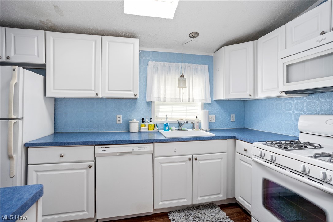 168 Coen Road Vermilion, OH 44089 - Photo 15 of 29 Kitchen with backsplash, white cabinets, wood-type flooring, dark countertops, and white appliances