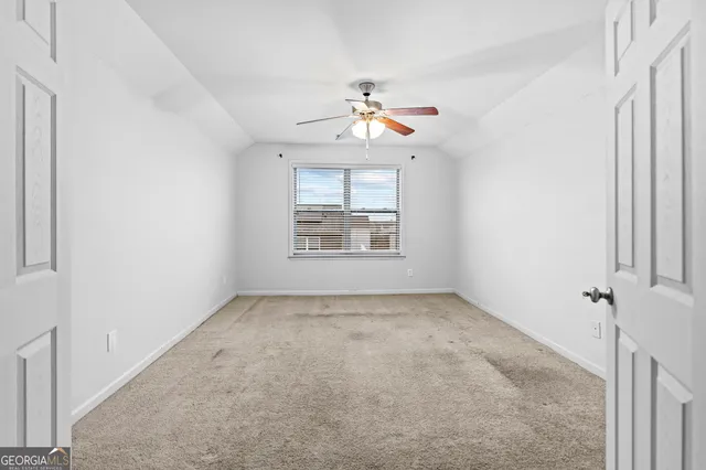an empty room with windows and chandelier fan