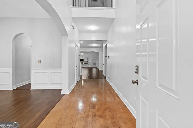 a view of a hallway with wooden floor and a bathroom