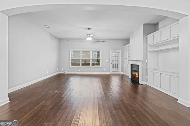 an empty room with wooden floor fireplace and windows