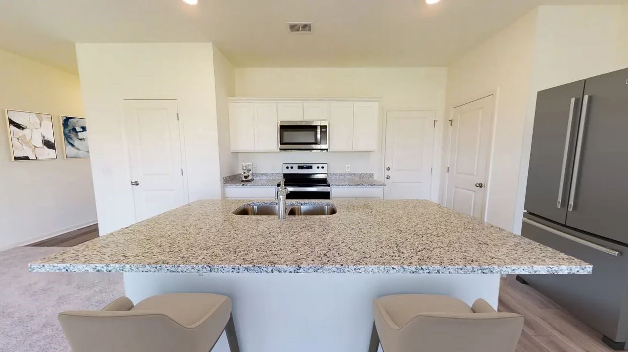 18216 Papuan Cove Elgin, TX 78621 - Photo 3 of 11 a kitchen with granite countertop a refrigerator and a sink