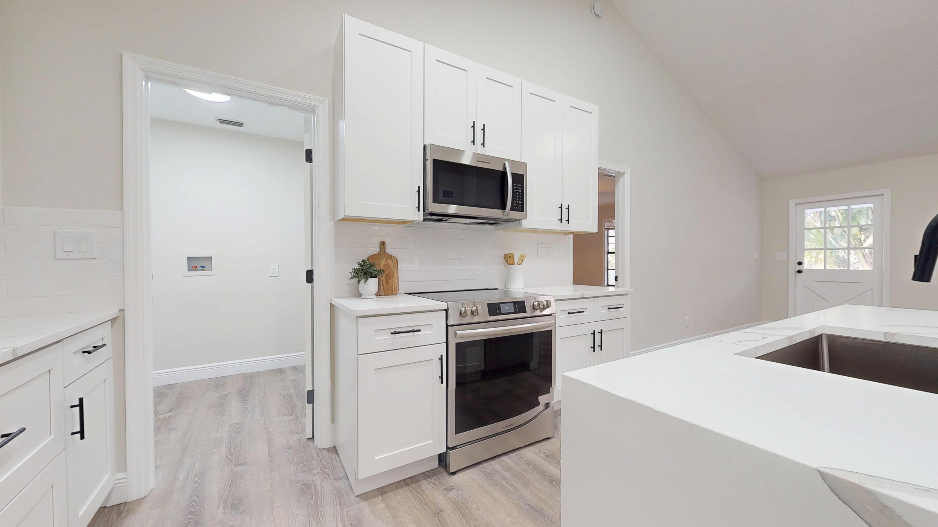 13018 153rd Road North Jupiter, FL 33478 - Photo 7 of 37 a kitchen with stainless steel appliances a stove microwave and sink
