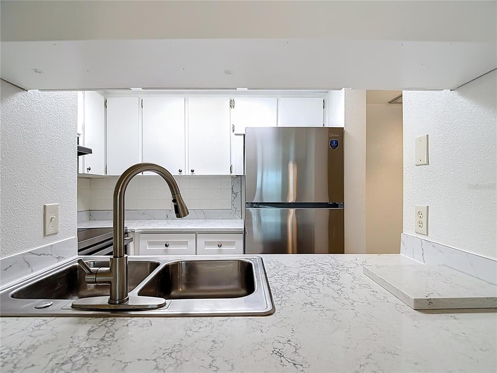 5132 Amulet Drive, Unit 105 New Port Richey, FL 34652 - Photo 12 of 42 a kitchen with a refrigerator and a sink