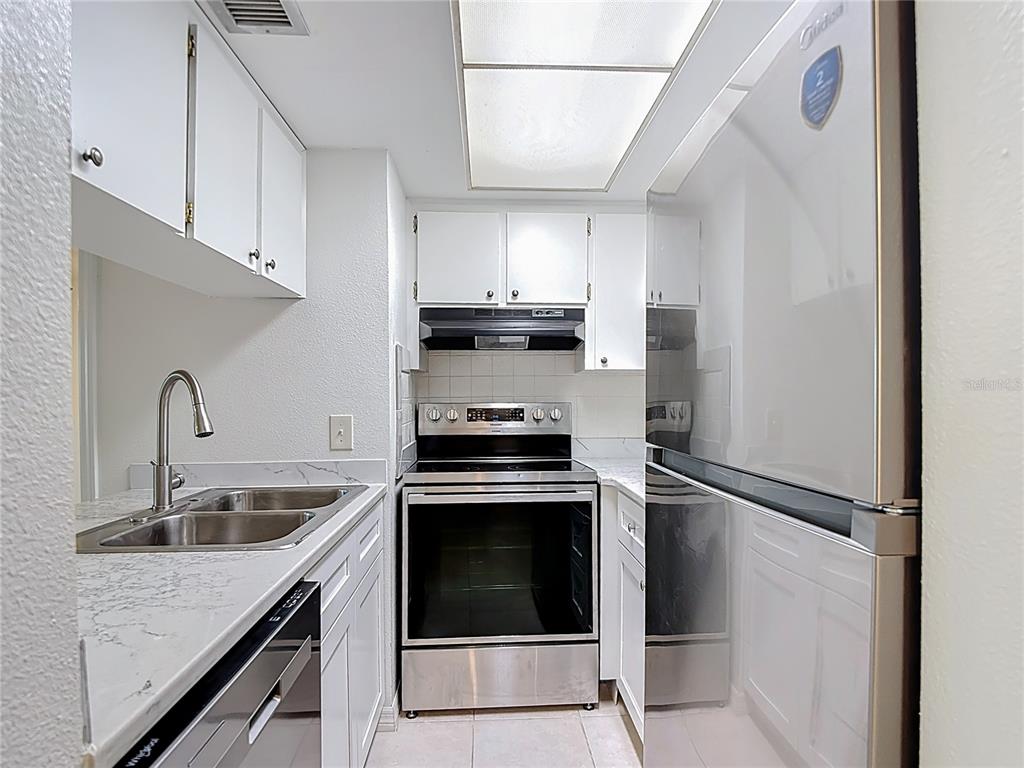 5132 Amulet Drive, Unit 105 New Port Richey, FL 34652 - Photo 13 of 42 a kitchen with stainless steel appliances granite countertop a sink stove and refrigerator