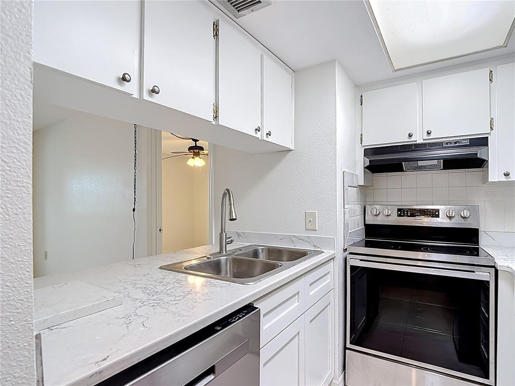 5132 Amulet Drive, Unit 105 New Port Richey, FL 34652 - Photo 14 of 42 a kitchen with a sink stove and cabinets