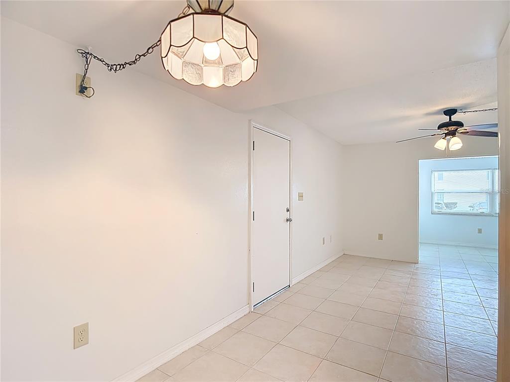 5132 Amulet Drive, Unit 105 New Port Richey, FL 34652 - Photo 29 of 42 an empty room with a chandelier fan and kitchen view
