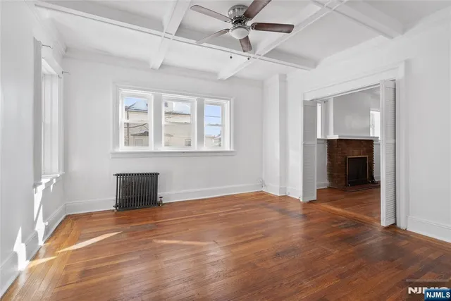 a view of an empty room with a window and a kitchen
