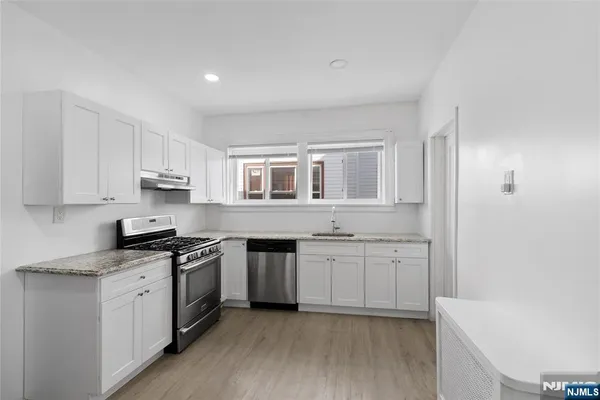a kitchen with granite countertop white cabinets and white appliances