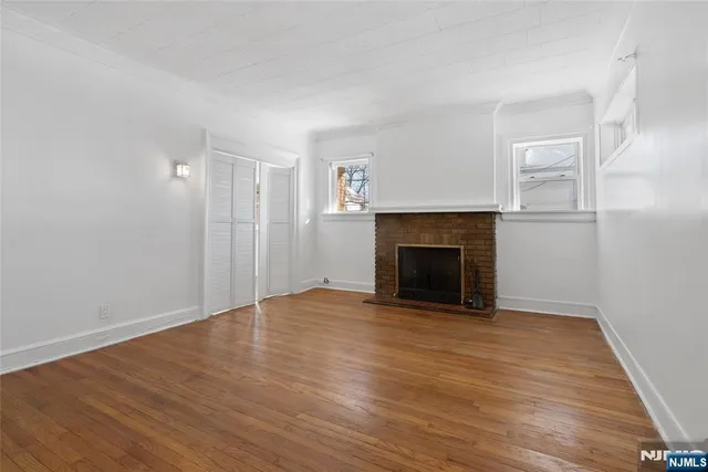 a view of empty room with wooden floor and fireplace