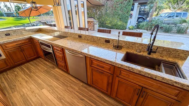 a kitchen with stainless steel appliances granite countertop a sink a stove and a wooden floors