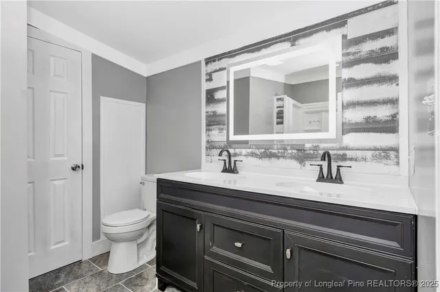 a bathroom with a granite countertop sink a toilet and a mirror