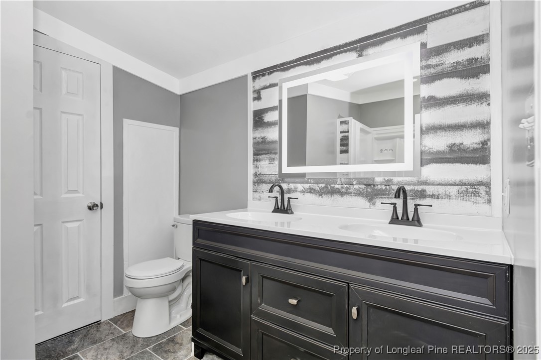 7225 Deep Branch Road Pembroke, NC 28372 - Photo 16 of 27 a bathroom with a granite countertop sink a toilet and a mirror
