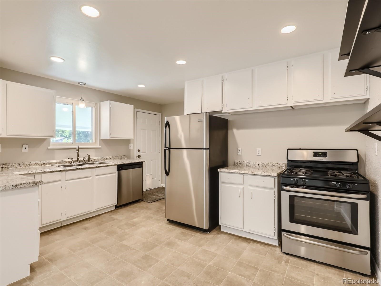 6930 North Locust Street Commerce City, CO 80022 - Photo 3 of 17 a kitchen with white cabinets and white appliances