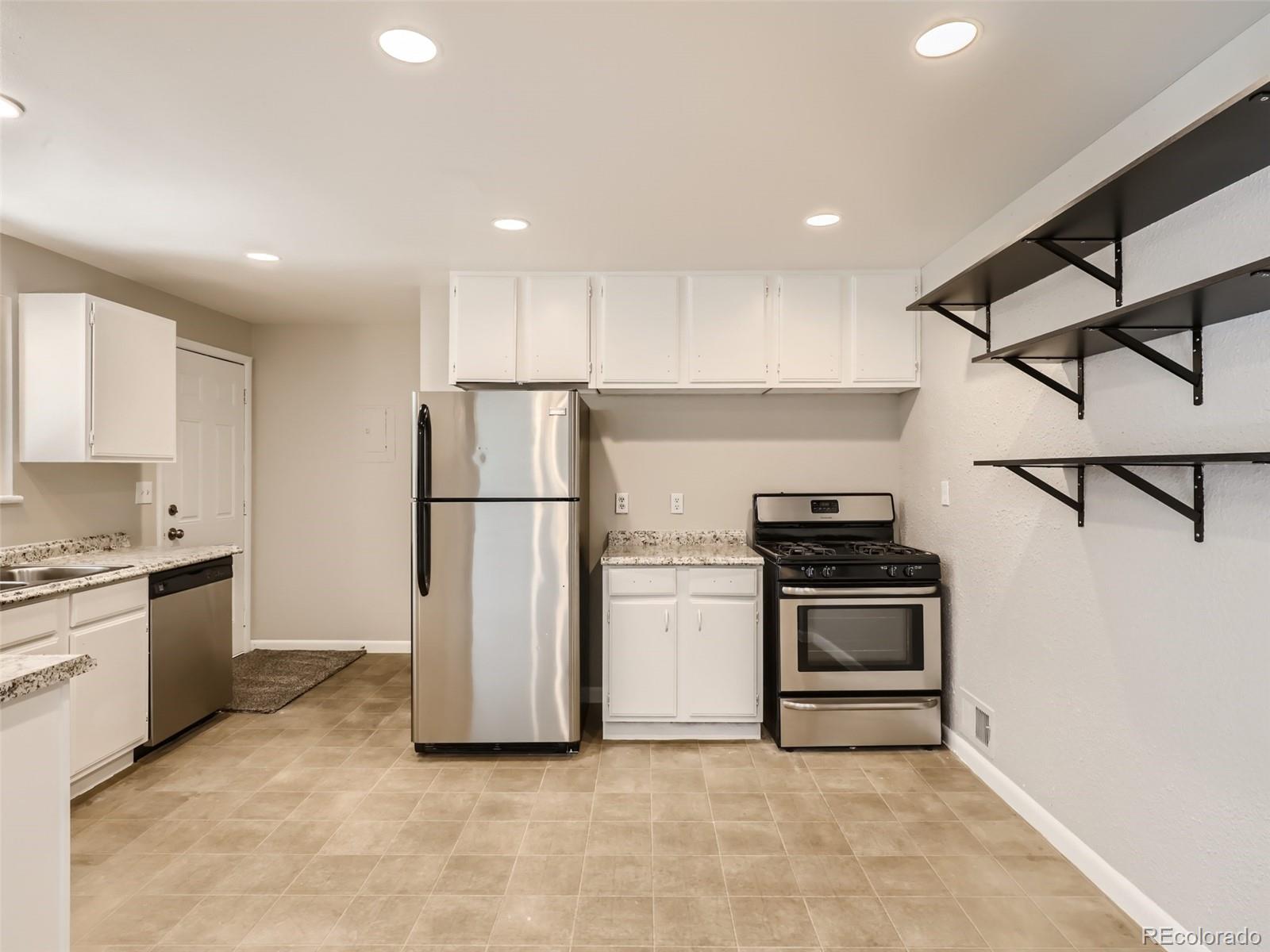 6930 North Locust Street Commerce City, CO 80022 - Photo 4 of 17 a kitchen with stainless steel appliances granite countertop a refrigerator a stove a sink and a microwave