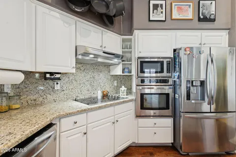 a kitchen with stainless steel appliances granite countertop a refrigerator sink and stove