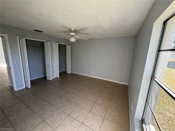 an empty room with windows and chandelier fan