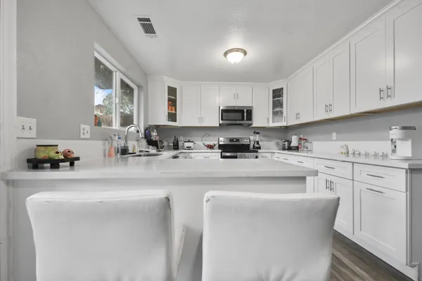 a kitchen with stainless steel appliances a sink a stove a refrigerator cabinets and a window