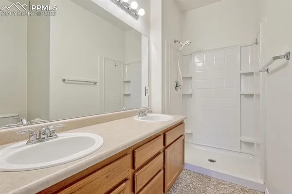 a bathroom with a sink double vanity granite tub shower and a mirror
