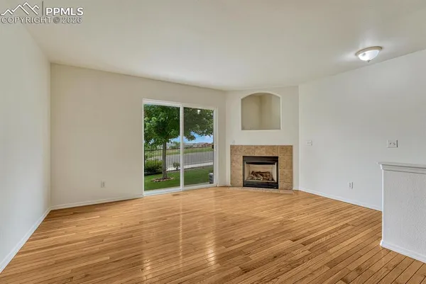 a view of empty room with wooden floor and fireplace