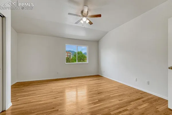 a view of an empty room with window and wooden floor