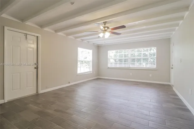 a view of an empty room with a window and wooden floor