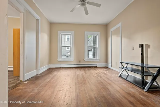 an empty room with wooden floor and windows