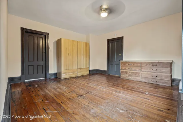 an empty room with wooden floor closet and windows