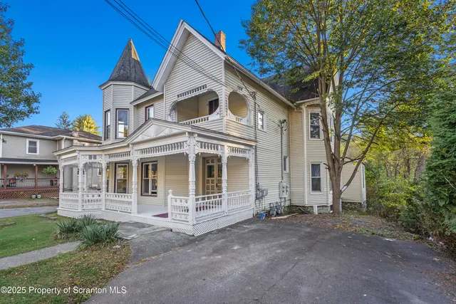 a view of a white house with large windows and a small yard